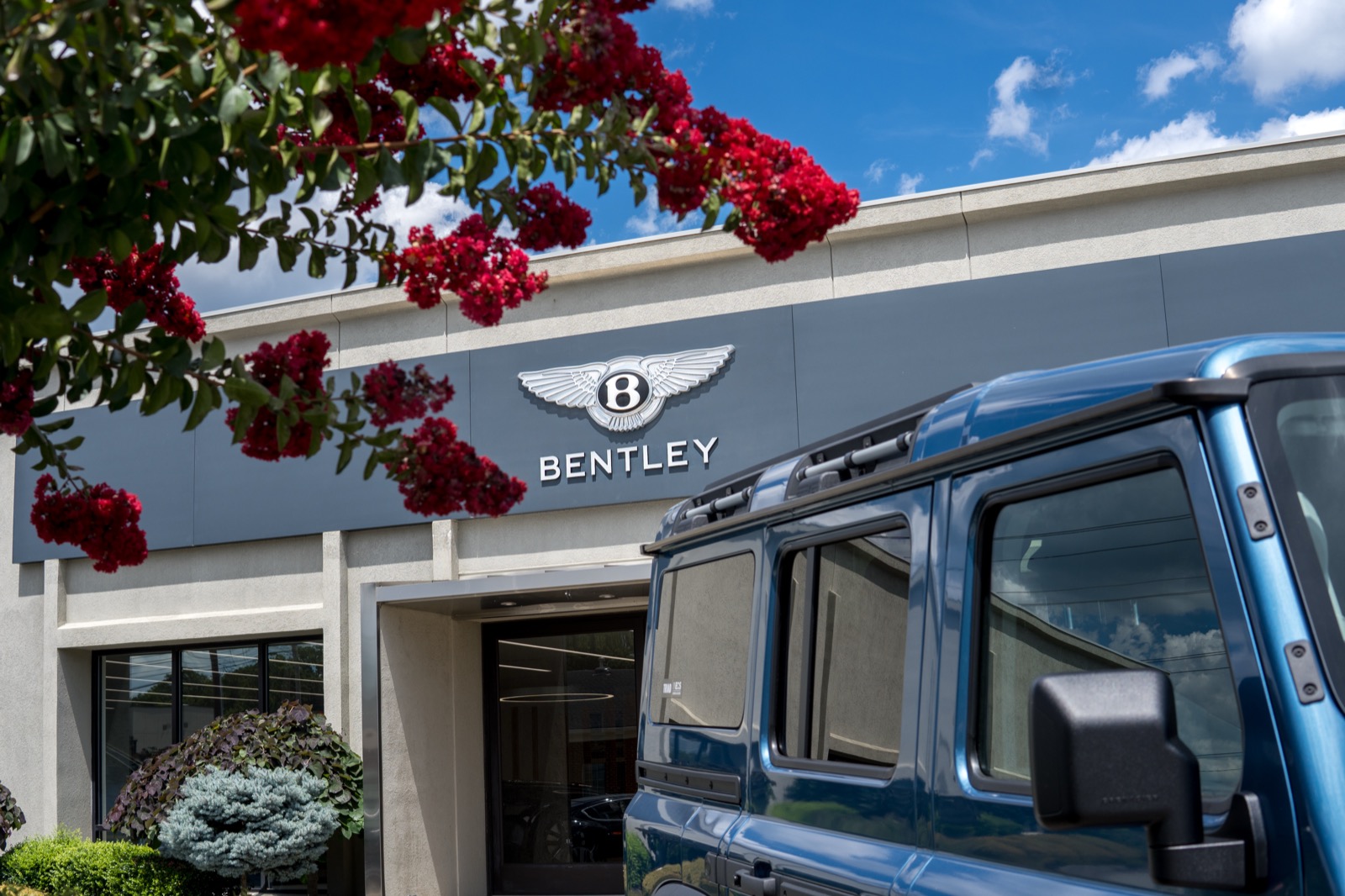 Bentley High Point dealership exterior with crepe myrtle in bloom and a Bentley Bentayga in the foreground.
